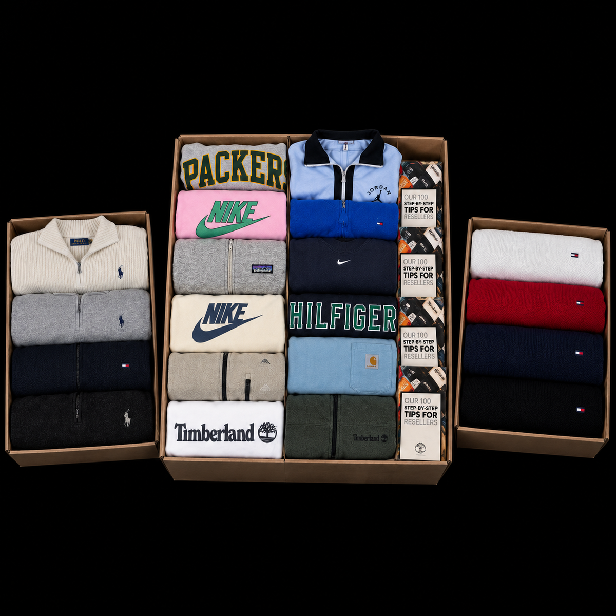 Three cardboard boxes filled with folded apparel on a black background. The center box contains folded quarter-zip sweatshirts and T-shirts from brands including Nike, Tommy Hilfiger, Timberland, and Selected 2.