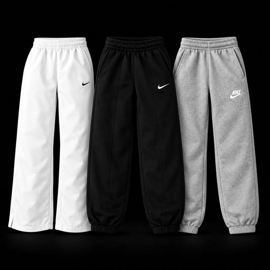 Three pairs of Nike jogger sweatpants are displayed side-by-side against a solid black background. From left to right, the colors are white, black, and heather gray.
